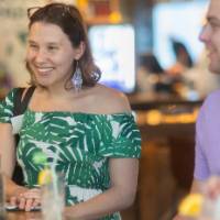 Woman standing at table as she smiles at something off camera